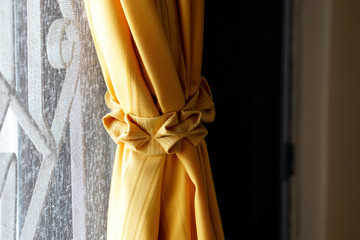 Old orange curtain and curtain tie with window frame as background of the house in Thailand