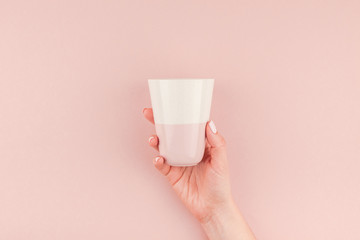 Woman hand holding coffee cup on pink background