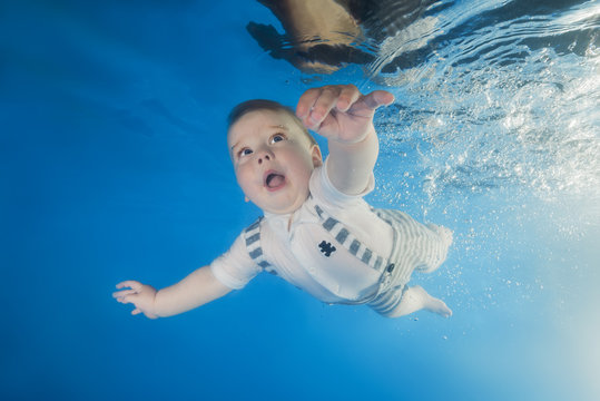  little boy in a suit swims underwater in the pool