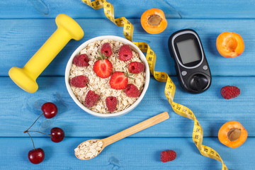Glucose meter for measuring sugar level, oatmeal with fruits and dumbbells