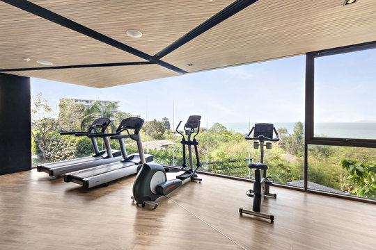Gym with Equipments fitness in topical ocean and sky view, luxury modern gyms wood room near sea