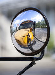 Traditional American school bus relected on its convex mirror