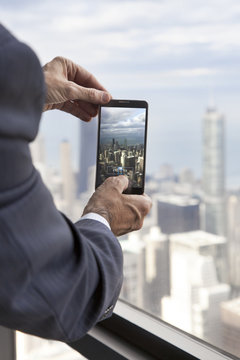 Businessman at Willis Tower taking a picture of Chicago skyline with his phone