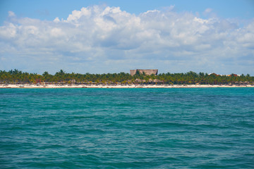 View of the shore from the boat on the waves in the warm Caribbean Sea. Riviera Maya Mexico. Summer sunny day, blue sky with clouds.