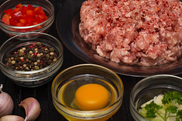 Minced meat. Ground meat with ingredients for cooking on a black background.