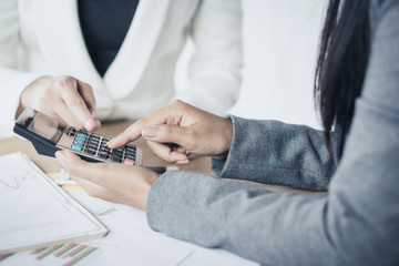 two business woman hand calculating together with financial data and business graph report on desk 