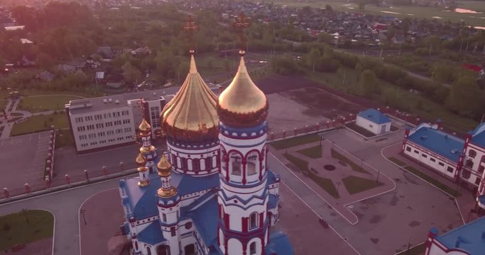 Aerial flying around new Church in small town. Christian temple and golden church dome at dawn. 4K