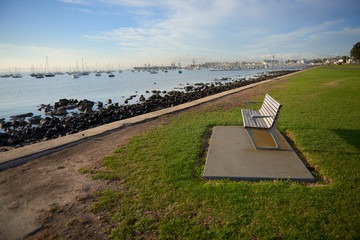 An empty bench on grass by the waters edge in the inspiring bright morning sun with a gorgeous view...
