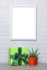 Mock-up of white frame with green gift box and small cacti