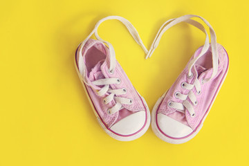 top view of little sneakers for baby on yellow background, fashion lifestyle