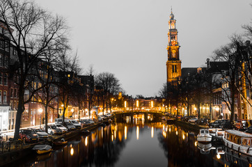 Fototapeta na wymiar Sunrise on a canal with old historical church on the horizon in Amsterdam water Holland bridge