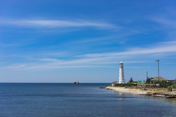 Fototapeta na wymiar seascape with beautiful white lighthouse on blue sky background.