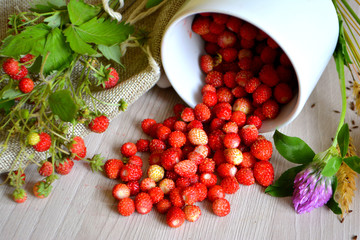 Wild strawberries and flowers on the table. Summer still life. Rustic style