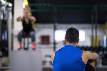 woman working out with personal trainer jumping on fit box