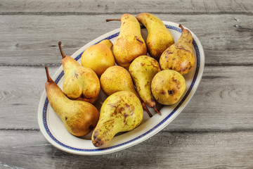 Table top view - oval plate with ripe pears placed on gray wood desk