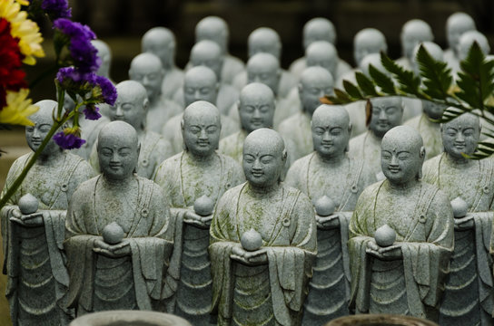 Statue of budhist monks standing seating praying meditating in a temple in Japan Asia