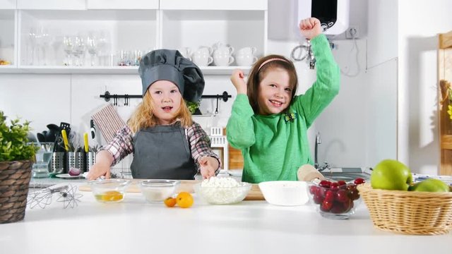 Two preschool little girls bakers have fun during cooking cheesecakes and desserts