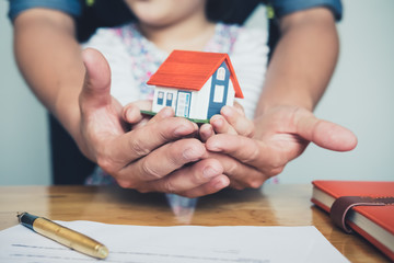 Hands holding small house after signing contract,concept for real estate,Insurance and safety...