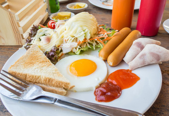 American breakfast : eggs,ham, bacon, .bread ,coffee and juice, and salad on the table
