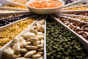 Indian Beans,Pulses,Lentils,Rice and Wheat grain in a white Sunburst or sun rays shape designer container , selective focus.