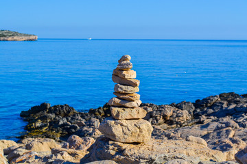 Calm pile of stones balance on a rock, in perfect harmony with the ocean background
