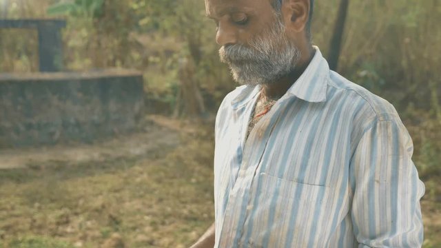 A farmer standing in the farmland making payment of farming accessories using Credit or Debit card. A working male or middle aged man using Credit/ATM card by mobile phone or cellphone or smartphone