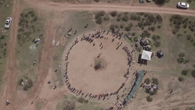 Aerial shot, native American Indians dance in ceremony, on sacred reservation land.