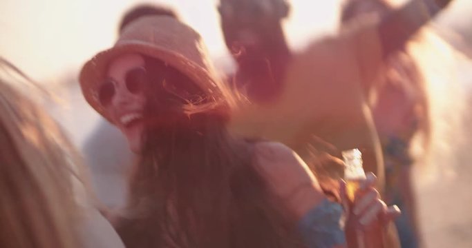 Young multi-ethnic hipsters dancing and drinking beer at beach party