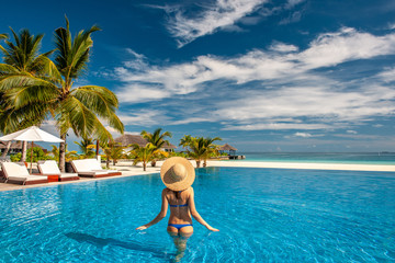 Woman with hat at beach pool in Maldives - obrazy, fototapety, plakaty