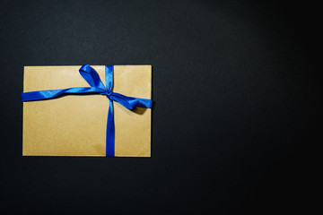 Brown envelope tied with a blue ribbon on a black background