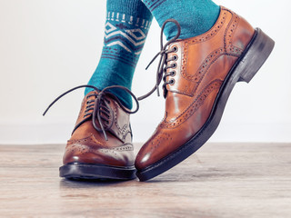 Classic brown men's brogues shoes and a man in blue socks. Men's stylish look.