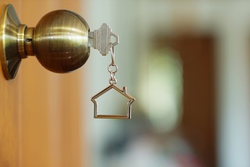 Home key with house keychain in keyhole, property concept