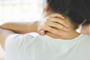 Closeup of young woman suffering from pain in neck while sitting on bed at home, People with body-muscles problem, Healthcare And Medicine concept