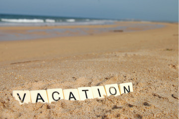 Letters of vacation on a sunny beach with sea in background