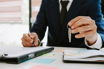 real estate agent holding house key to his client after signing contract,concept for real estate,...