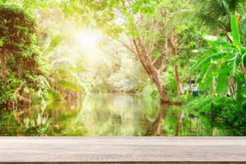 Empty wooden desk of free space and spring time with Morning sun light with wind blowing leaves in the lake park,Template mock up for display montages of product.