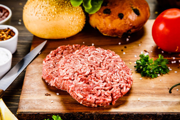 Fresh raw steaks on cutting board with vegetables