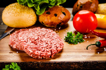 Fresh raw steaks on cutting board with vegetables