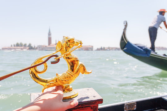 Figure of a sea horse on a gondola. Gondolier in the background. Venice. Italy.