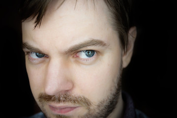 Obraz premium Man with suspicious face on dark background.