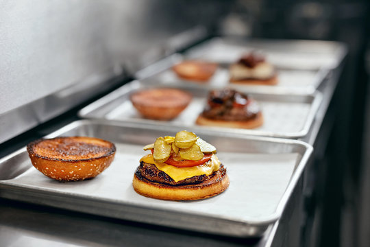 Burger Restaurant. Closeup Of Burgers Cooking In Kitchen