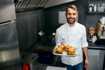 Chef With Burgers In Restaurant Kitchen