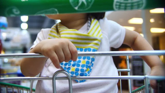 baby sitting seat in shopping cart, close-up small hand holding stainless rail