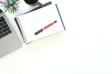 Workspace laptop computer, notepad paper, pen and coffee cup on office work table with top view.