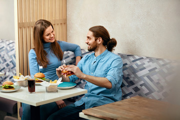 Obraz premium Couple With Burgers In Cafe