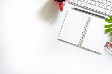 Office desk workspace top view with cup of coffee, computer, notebook paper, pencil and plant decoration.