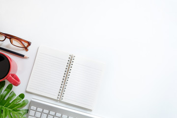 Office desk workspace top view with cup of coffee, computer, notebook paper, pencil and plant decoration.