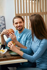 Couple With Burgers In Cafe