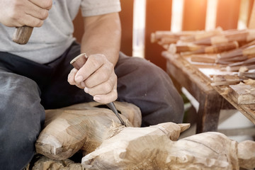 Obraz na płótnie Canvas Closeup Old man Hands of craftsman wooden carve with a gouge in the hands on the workbench in carpentry
