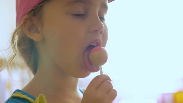 Little girl enjoying a lollipop while staring at camera. Child eating candy, sweets, sugar